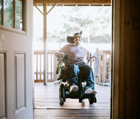 man is on chair wheel behind the door of the house