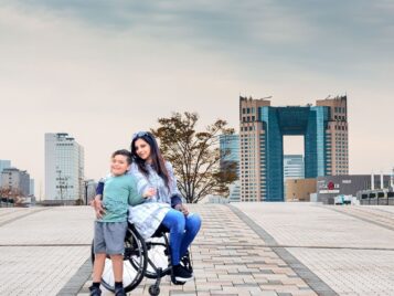 Woman is sitting on chair wheel while taking a picture with child