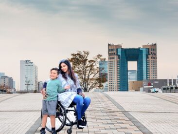 Woman is sitting on chair wheel while taking a picture with child